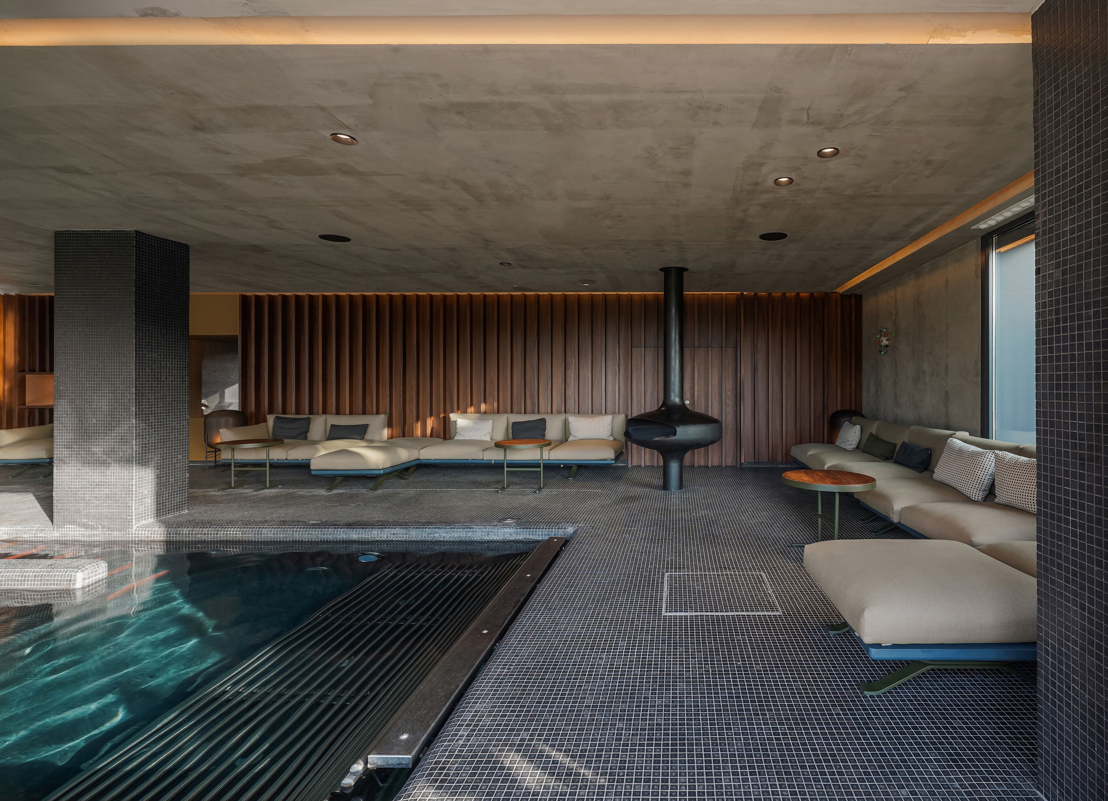 A modern indoor pool area with a lounge and seating.