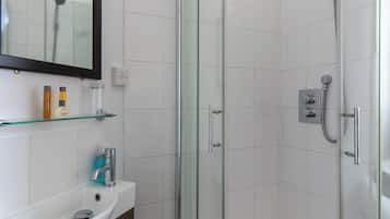 A modern bathroom with a glass-enclosed shower, a white sink, and a mirror above it.