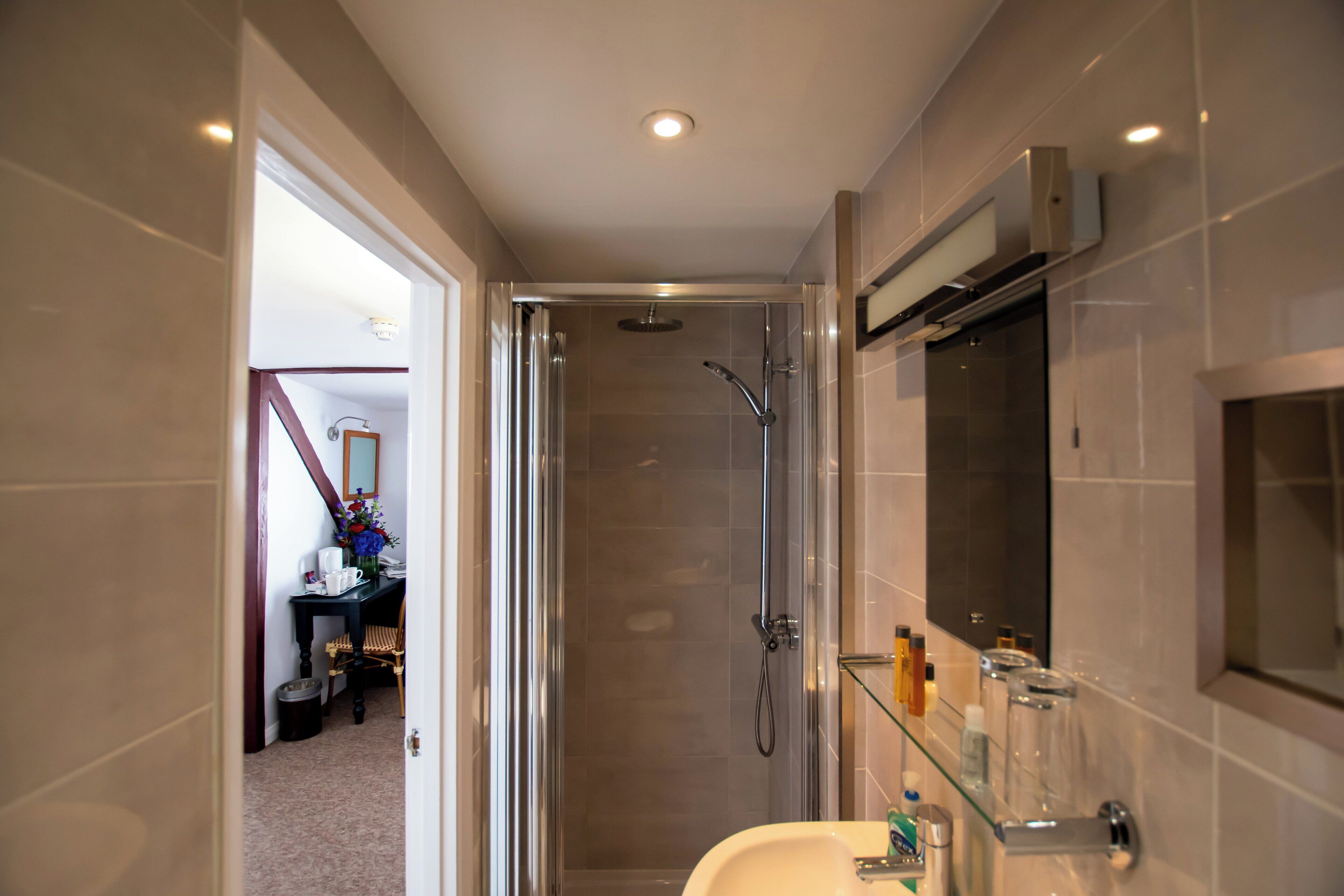 Un bany modern amb un cubicle de dutxa de vidre, un lavabo blanc i un mirall a sobre.