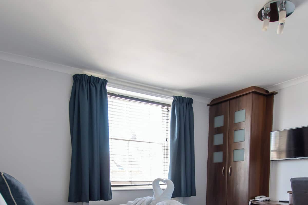 A hotel room with a bed, a desk, a wardrobe, and a television.