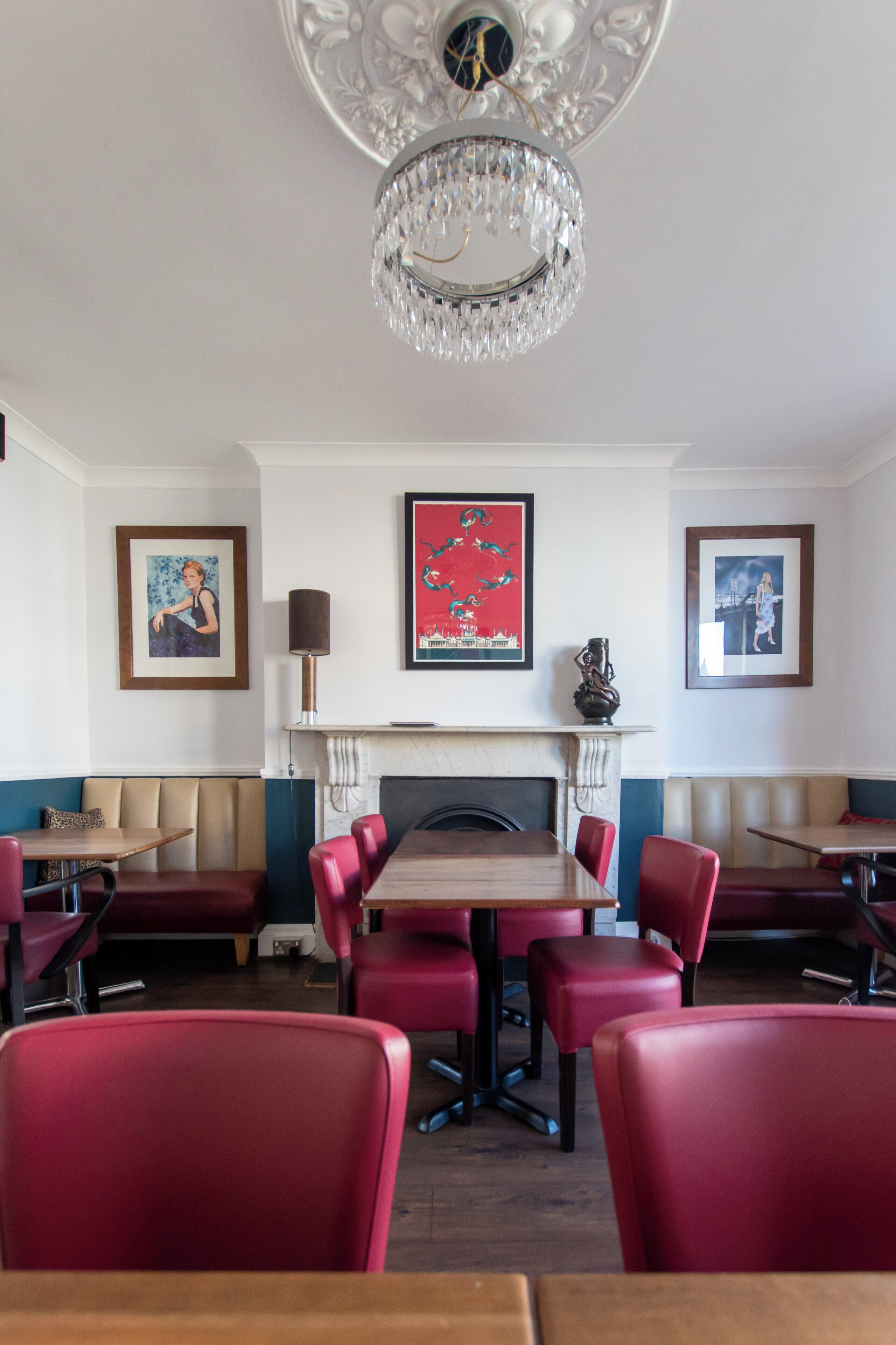 A dining area with red upholstered booths, a chandelier, and framed artwork on the walls.