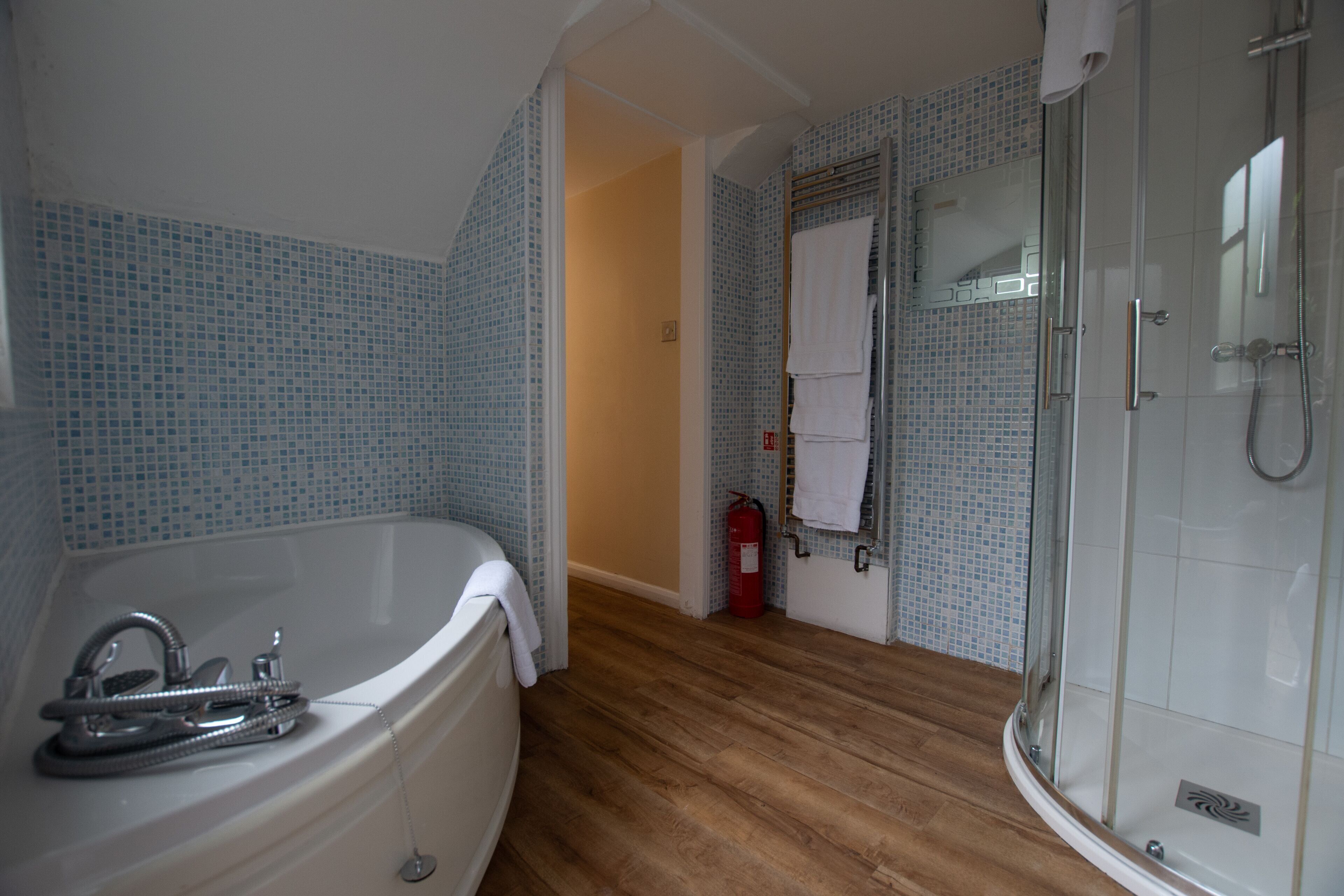 A bathroom with a bathtub, shower, and tiled walls.