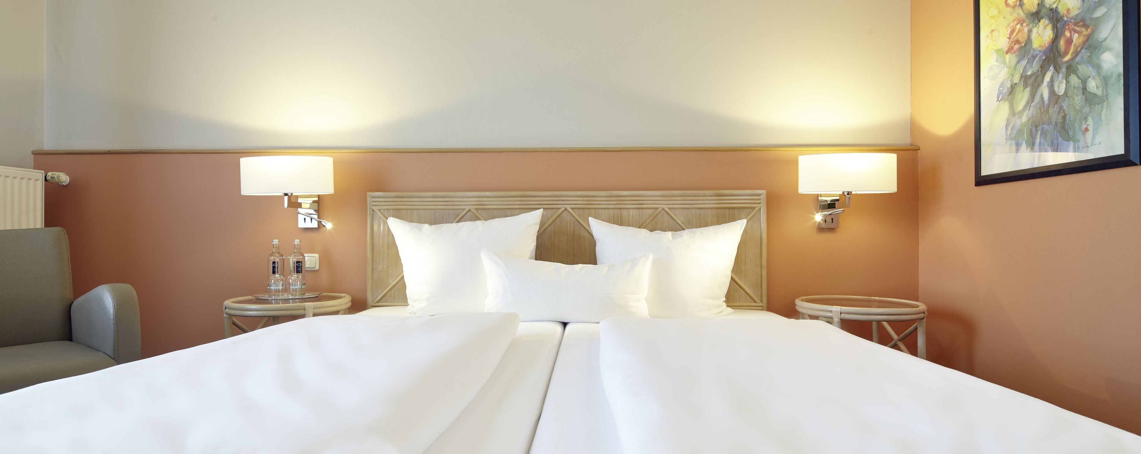 Ein Hotelzimmer mit einem großen Bett, zwei Nachttischen mit Lampen, einem Kopfteil und einem Bild an der Wand.