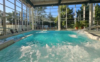 Una piscina interior con agua cristalina, rodeada de amplias ventanas y un techo cubierto.