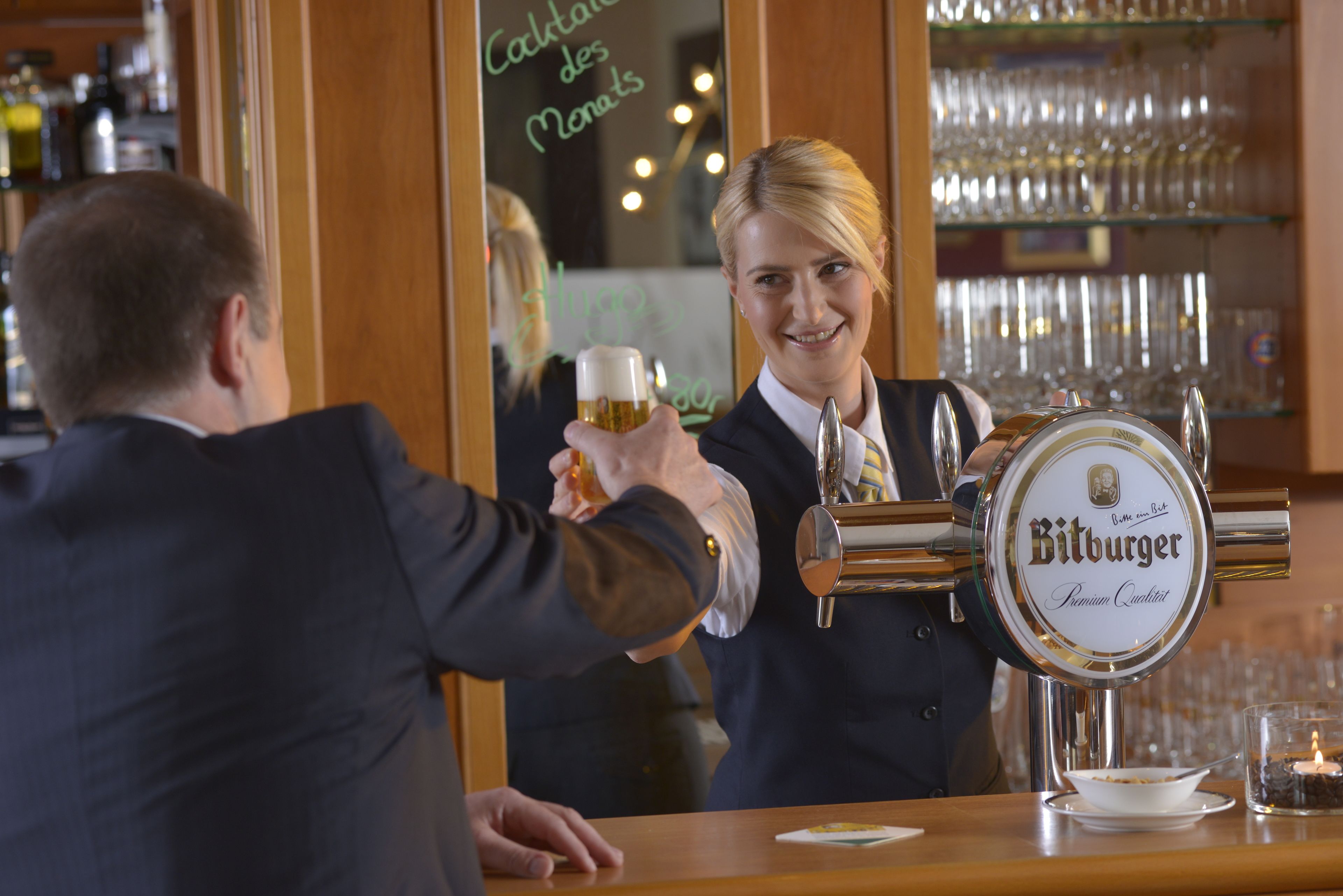 Een barsetting met een biertappkraan waarop 'Bitburger Premium Quality' staat en een biertje dat wordt geschonken.