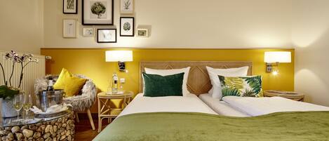 A hotel room with a bed, two bedside tables, a chair, a small table with a lamp, and framed pictures on the wall.