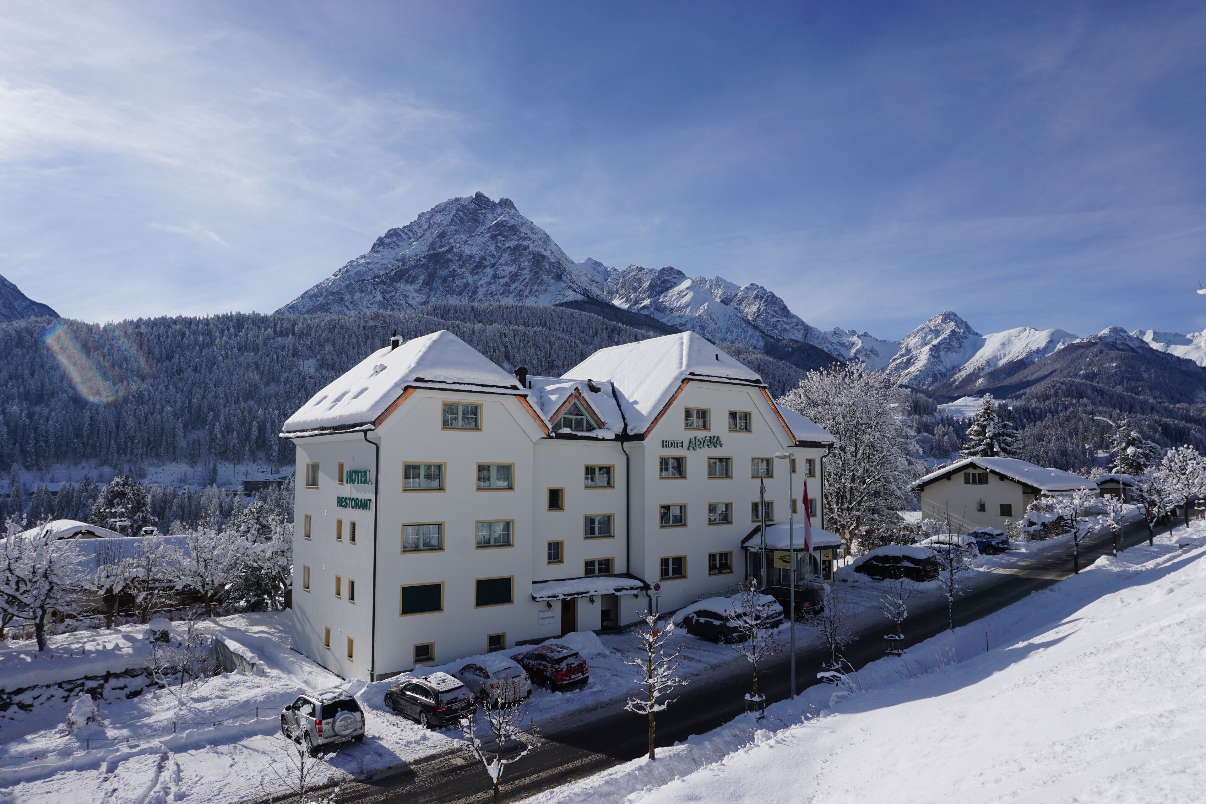 Un hôtel à étages, avec un toit enneigé et une vue sur les montagnes en arrière-plan.
