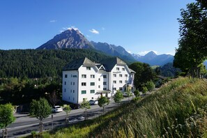 A hotel with a modern design, located on a hillside with a mountain backdrop. - Typically Swiss Hotel Altana (Scuol)