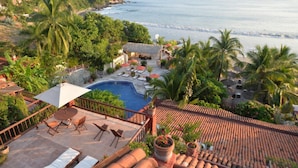 A resort with a swimming pool, lounge chairs, and a view of the sea. - Hotel Aura del Mar (Zihuatanejo)