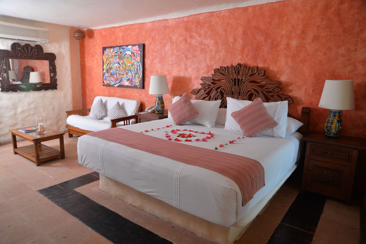 Une chambre d’hôtel avec un grand lit, deux tables de chevet, une chaise et un élément décoratif mural.