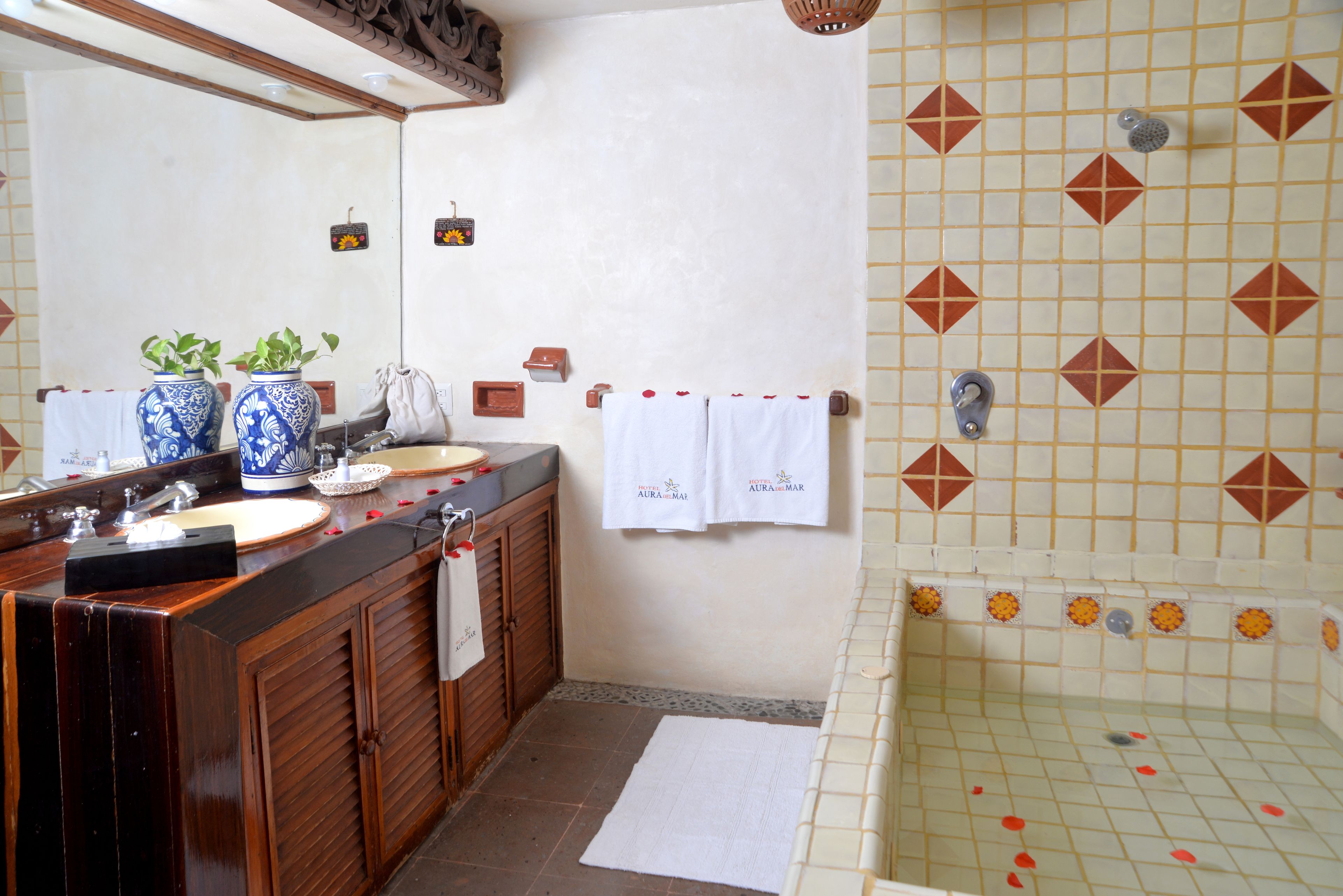 Ein Badezimmer mit einem Holzwaschtisch, zwei Waschbecken, einem großen Spiegel und einem Duschbereich mit dekorativen Fliesen.