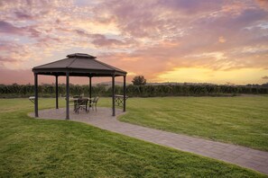 A gazebo with a table and chairs, surrounded by a grassy lawn and a paved walkway. - Best Western Plus Grapevine Inn (Sunnyside)