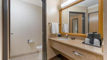 Ein Badezimmer in einem Hotel mit Waschbecken, Spiegel, Handtuchhalter und Toilette.