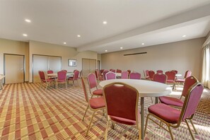 A conference room with a checkered carpet, round tables, and red chairs.