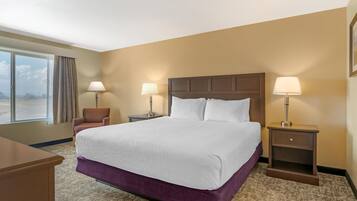 A hotel room with a large bed, two bedside tables with lamps, a chair, and a window with curtains.