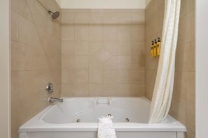 A bathroom with a bathtub, shower, and a towel rack with toiletries. - Best Western Plus Grapevine Inn (Sunnyside)