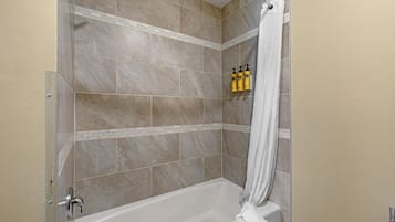 A bathroom with a shower, a bathtub, and a towel rack with bottles.