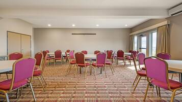 A conference room with round tables and chairs, a patterned carpet, and a large window with curtains.