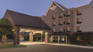 A Country Inn & Suites by Wyndham building with a covered entrance, multiple windows, and a brick facade. - Country Inn & Suites by Radisson, Raleigh-Durham Airport, NC (Morrisville)