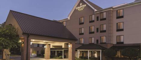 A Country Inn & Suites by Wyndham building with a covered entrance, multiple windows, and a brick facade.