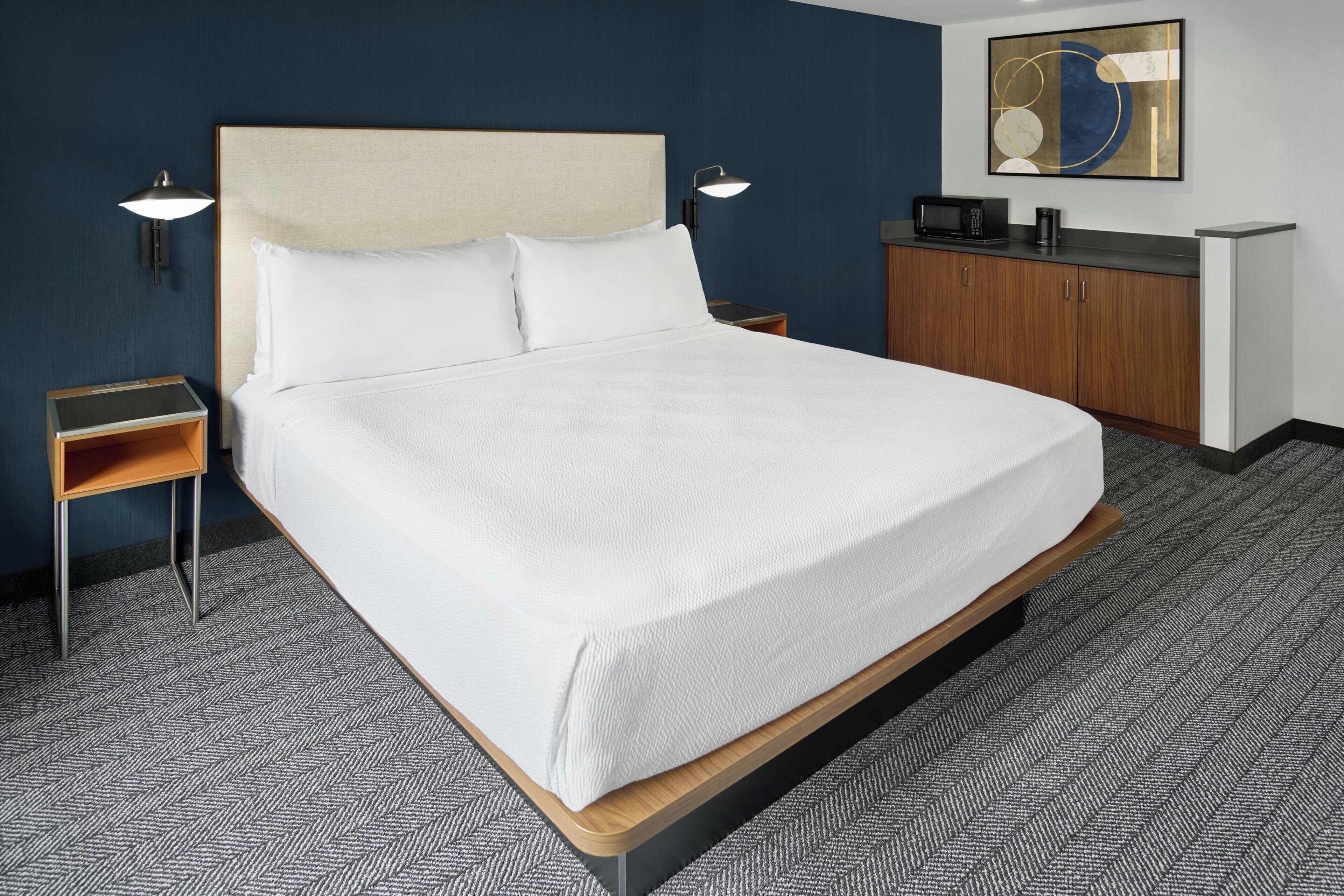A neatly made bed with white linens in a hotel room.