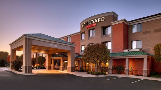 Hotel Courtyard Marriott con entrada cubierta, fachada de ladrillo y un cartel que indica una altura libre de 4,1 metros.