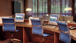 Habitación de hotel con zona de escritorio que incluye tres computadoras, un televisor y un sofá.