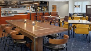 Un restaurante moderno con zona de bar, diversas opciones de asientos, incluyendo mesas y cabinas, y un tablero de menú a la vista.
