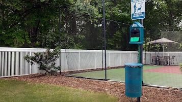 A fenced outdoor area with a trash bin and a sign about pet waste.