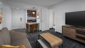 Une chambre d’hôtel moderne équipée d’un canapé, d’une table à manger, d’un téléviseur et d’un coin cuisine.