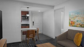 A compact living space with a kitchenette, a dining area, and a sofa with a cushion.