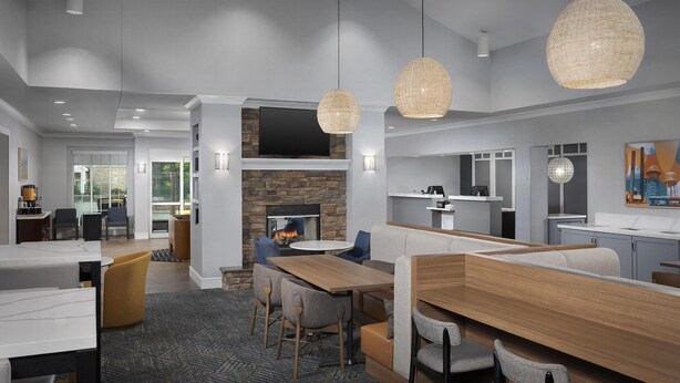 Un hall d’hôtel moderne doté d’une cheminée, d’espaces de détente, d’une cuisine et d’un coin repas.