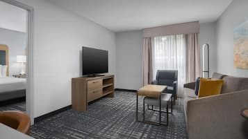 Habitación de hotel con cama, escritorio con televisor, sofá y sillón.