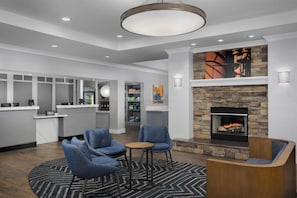 A modern lobby with a fireplace, seating area, and a reception desk. - Homewood Suites by Hilton Birmingham South Inverness (Birmingham)