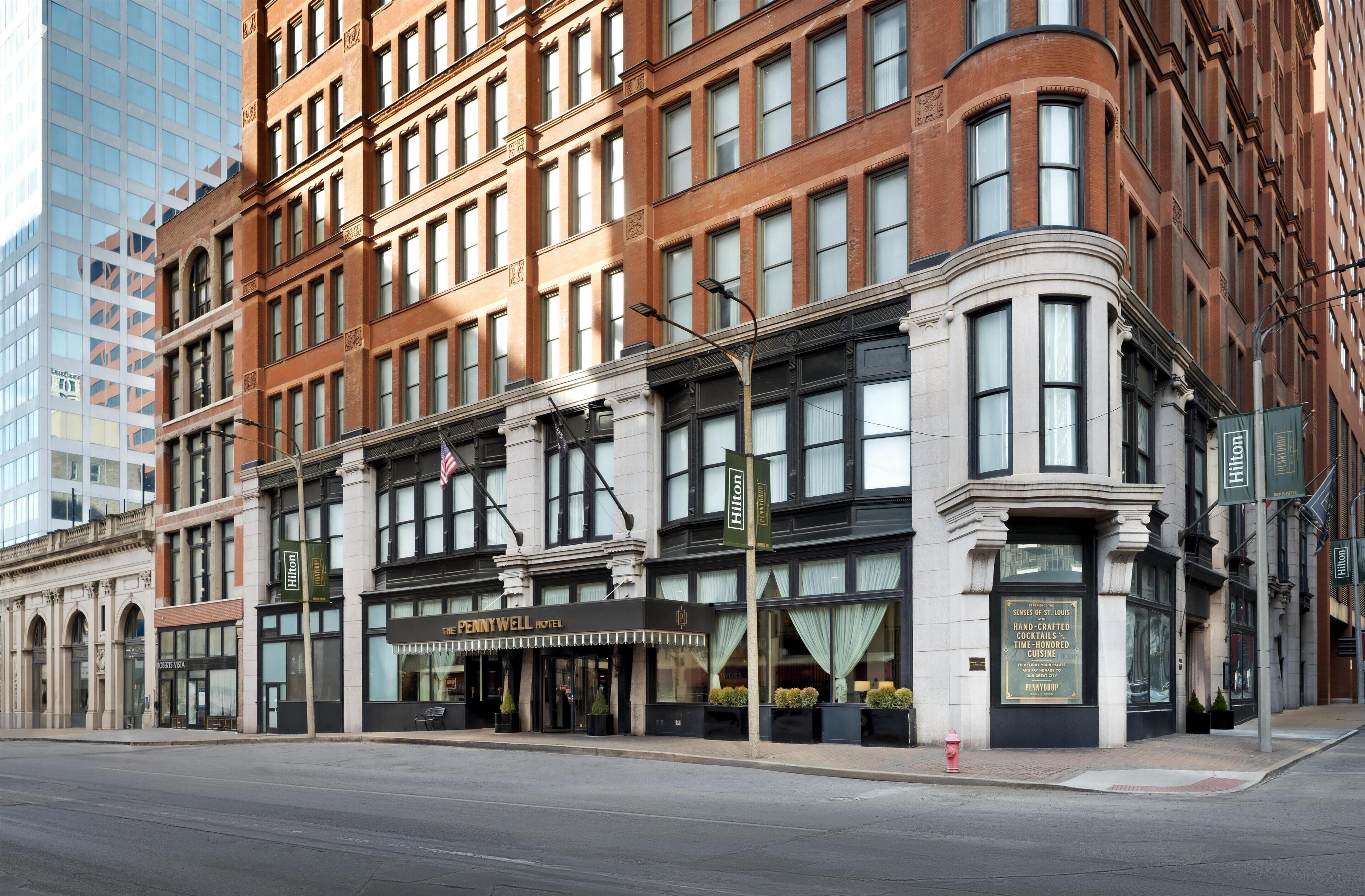 A historic building with a corner entrance, a prominent "Penny Well Hotel" sign, and a fire hydrant on the sidewalk.