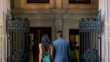 A man and a woman exiting a building through a black wrought iron gate.