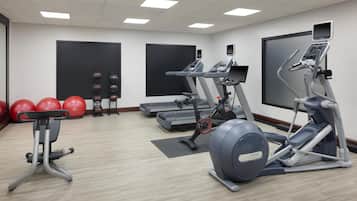 A gym with treadmills, elliptical machines, and red exercise balls.