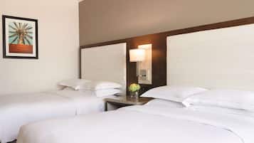 A hotel room with two beds, a nightstand with a lamp, and a framed picture on the wall.