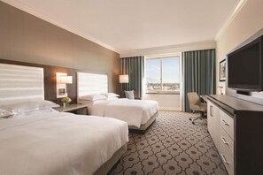 A hotel room with two beds, a desk, a television, and a large window with a view. - Hilton Los Angeles/San Gabriel (San Gabriel)