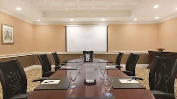 A conference room with a long table, black chairs, a projector screen, and a large water dispenser.