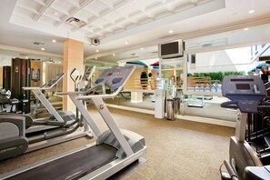 Une salle de sport équipée de tapis de course, d’appareils d’exercice et d’un grand miroir.