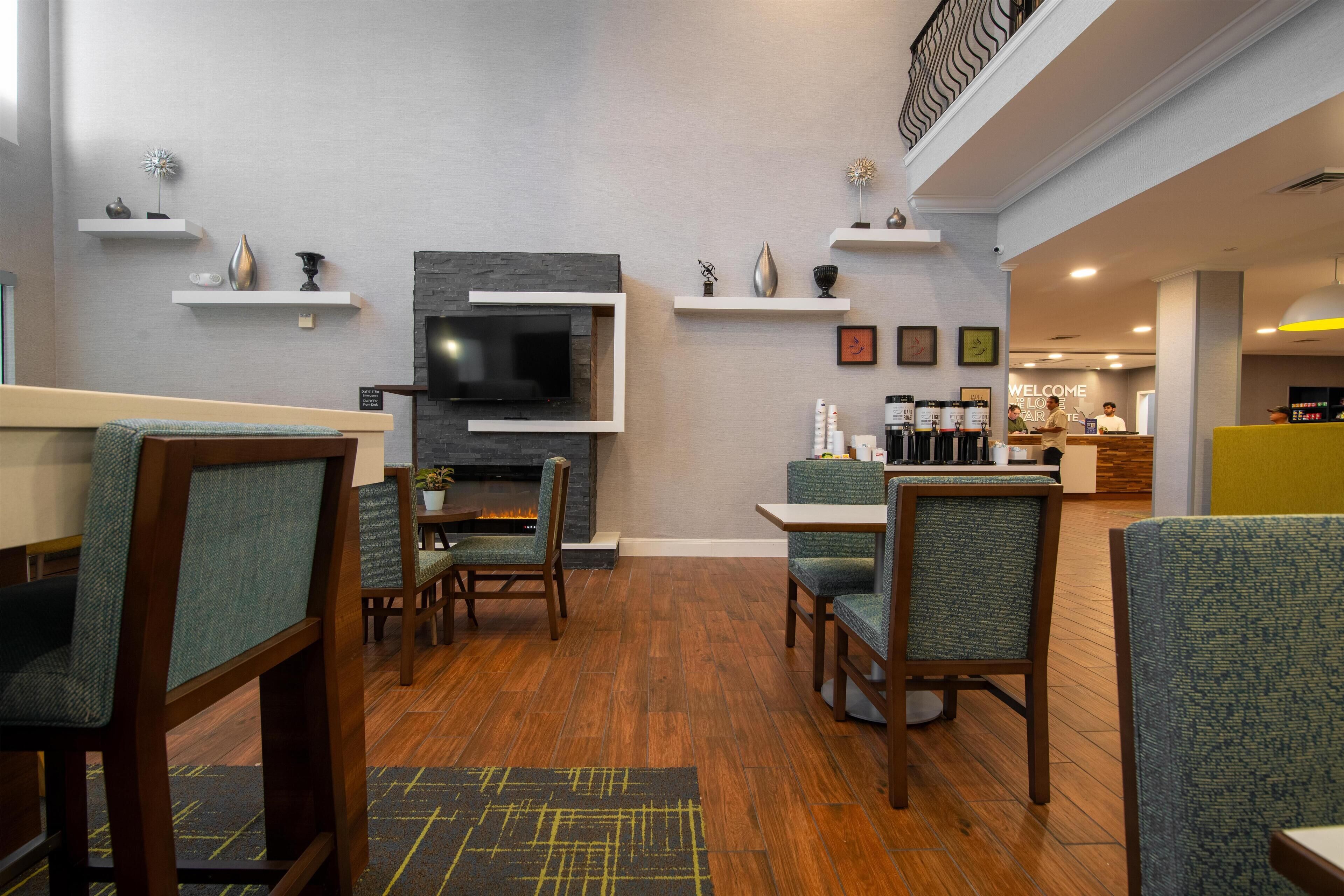 A modern hotel lobby with a fireplace, seating area, and a reception desk.