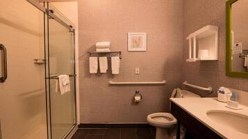 Un baño moderno con cabina de ducha de vidrio, inodoro blanco y tocador con espejo.