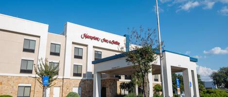 Entrada de un hotel con un letrero que dice 'Hampton Inn & Suites'.