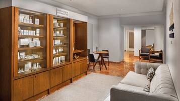 A modern living room with a wooden cabinet, a grey sofa, and a dining area with a table and chairs.