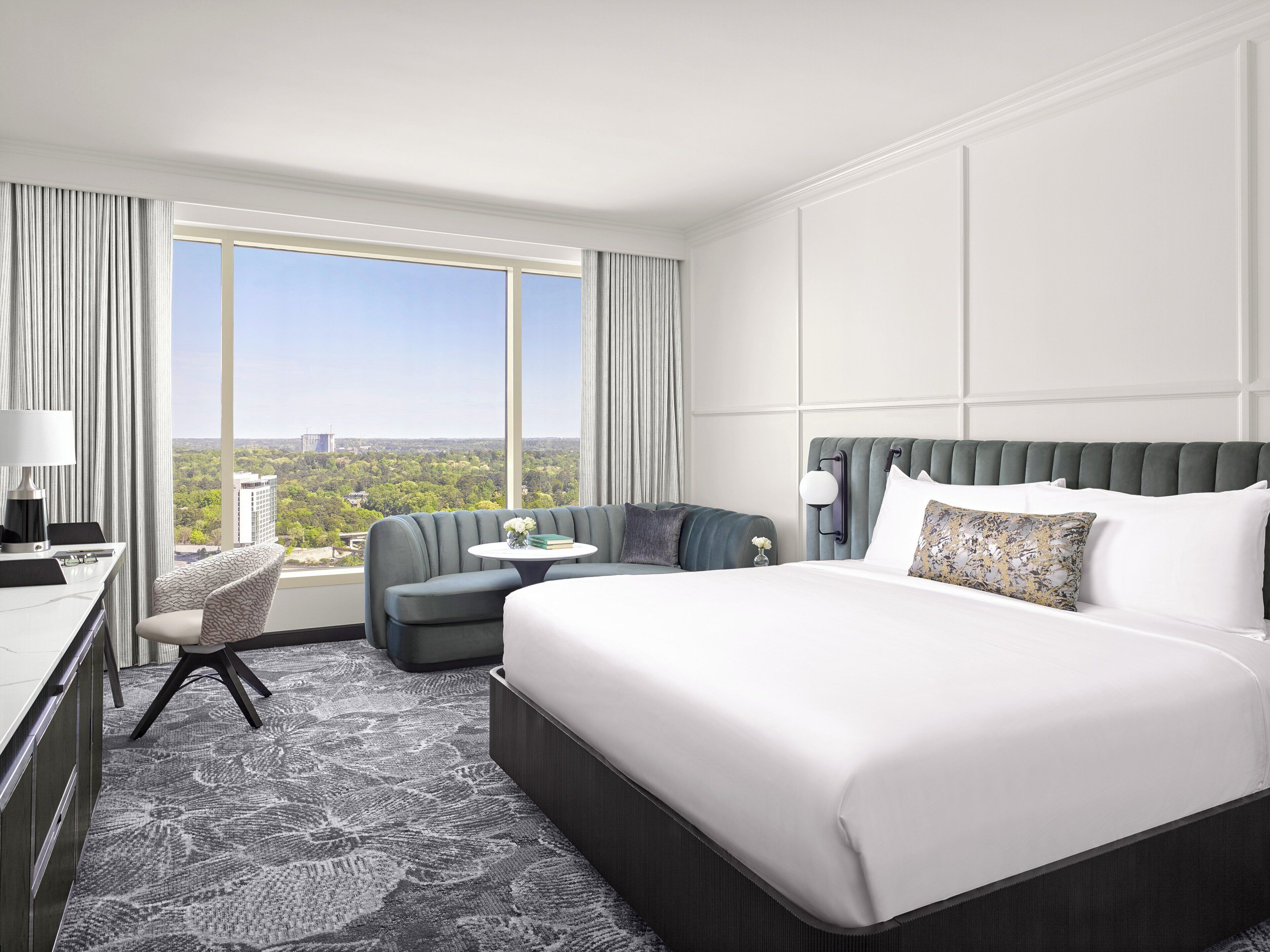 Habitación de hotel con una cama grande, un escritorio, una silla y vistas a la ciudad.