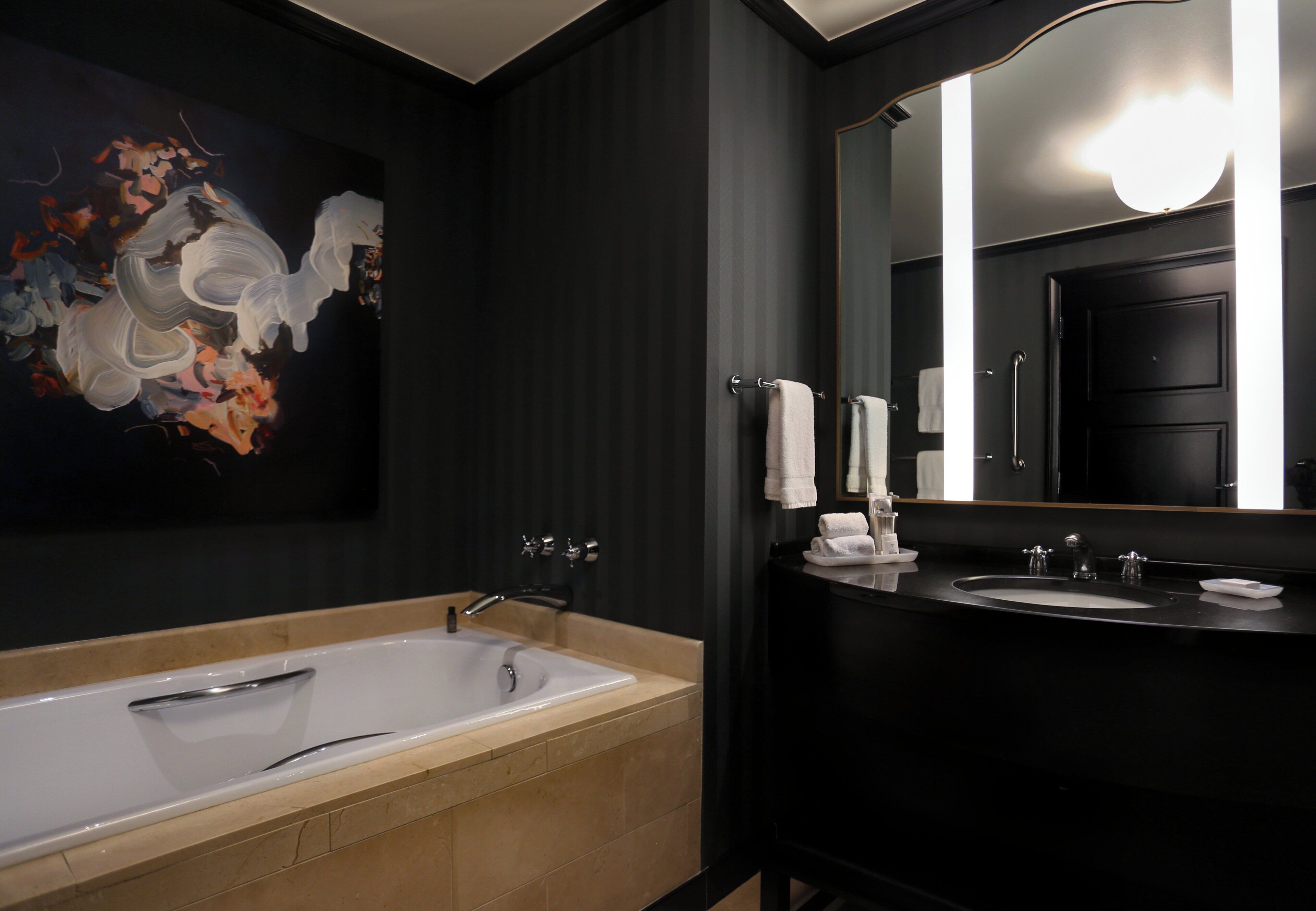 A modern bathroom with a large bathtub, a double sink vanity, and a large mirror.