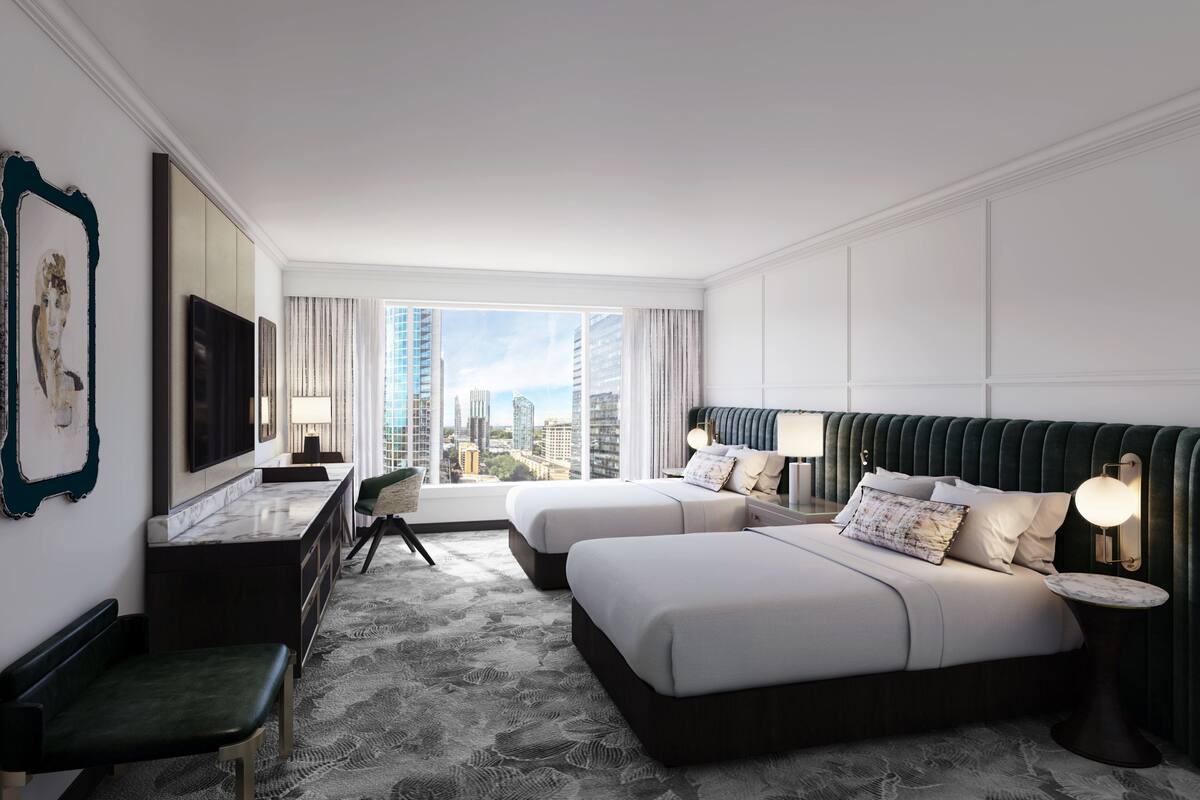 A hotel room with two beds, a desk, a chair, a TV, and a city view.
