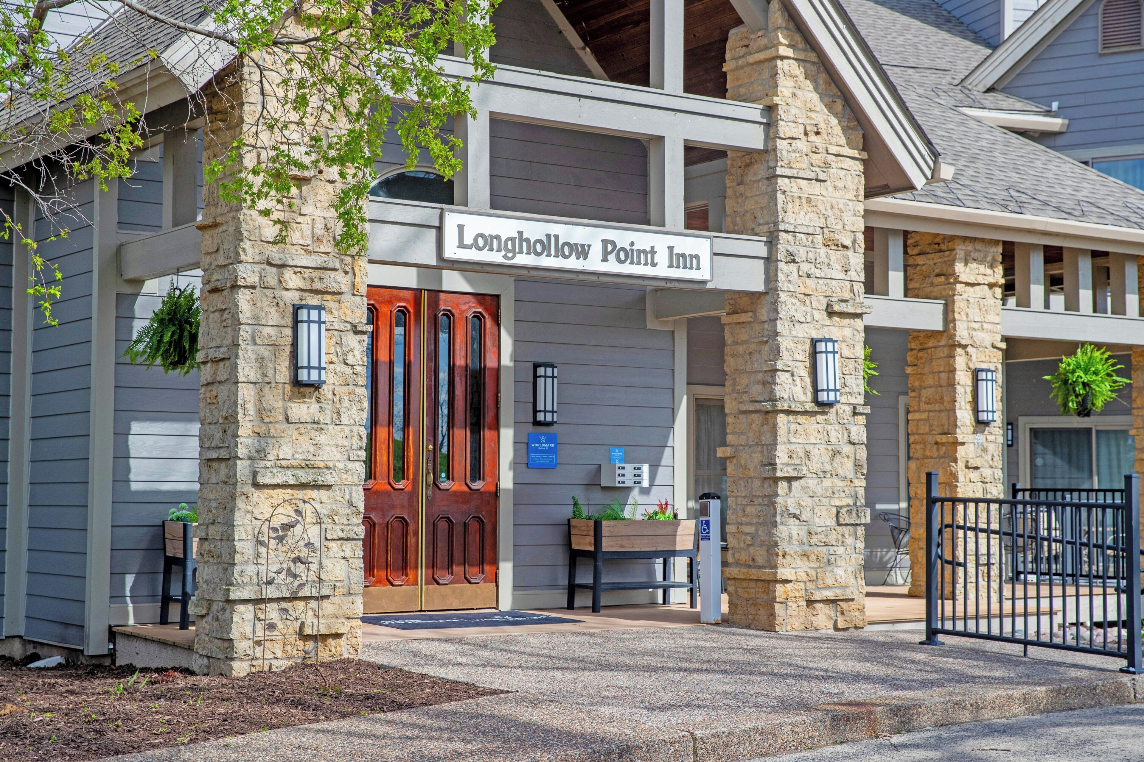 Une entrée en pierre avec une porte rouge et une enseigne indiquant : « Longhollow Point Inn ».