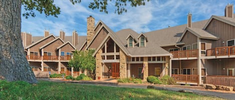 A multi-story hotel with stone and wood exteriors, balconies, and a well-maintained lawn.